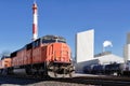 A train rolls down the track past an industrial manufacturing plant