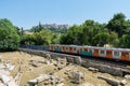 A train is running on the rayway passing through the Ruins of Ancient Agora and background of Acropolis of Classical Athens of Royalty Free Stock Photo