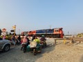 A Train with a Red and Blue Locomotive Crossing a Crowded Road