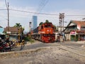 A Train with a Red and Blue Locomotive Crossing a Crowded Road