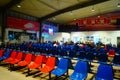 Train station passenger waiting area, rows of chairs and a number of male and female passengers