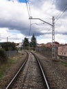 Train track on a curved path under the catenary wires and a sign on the side of the track