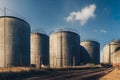 a train track runs between three large tanks on a sunny day in the country side of a city