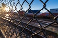 Train tracks through chainlink fence at sunset Royalty Free Stock Photo