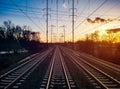 Train tracks converging on the horizon landscape with colorful sunset light in the background sky Royalty Free Stock Photo