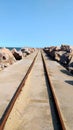 Train tracks in cassino beach. Landscape of rails at sea with rocks and blue sky. Royalty Free Stock Photo