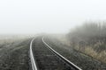 Train tracks receding into fog.