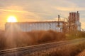 A train tracks run through a field with a large building in the background Royalty Free Stock Photo