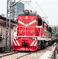 a train traveling down tracks next to a building and trees Royalty Free Stock Photo