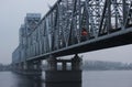 The train is traveling over a bridge over a river in thick fog. Gray background, color photo. Mystical picture