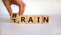 Train your brain. Hand turns a cube and changes the word `train` to `brain` on wooden cubes. Beautiful white background, copy