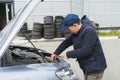 Trainee auto mechanic works in a garage, outdoors. Automobile Repair Service Concept Royalty Free Stock Photo