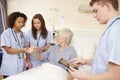 Trainee Nursing Staff By Female Patient's Bed In Hospital