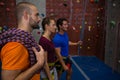 Trainer assisting athletes in wall climbing at club Royalty Free Stock Photo