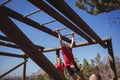 Trainer assisting girl to climb monkey bars during obstacle course training Royalty Free Stock Photo