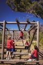 Trainer assisting girl to climb monkey bars during obstacle course training Royalty Free Stock Photo