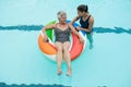 Trainer assisting senior woman on inflatable ring in swimming pool Royalty Free Stock Photo