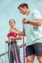 Trainer and female athlete using rubber bands for training outdoors in the city