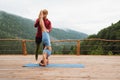 Trainer helping woman doing headstand yoga exercise during workout on terrace in mountains Royalty Free Stock Photo