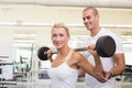 Trainer helping woman with lifting barbell in gym Royalty Free Stock Photo