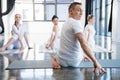 Trainer and his group practicing half spinal twist pose in gym