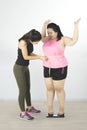 Trainer measuring belly of fat woman