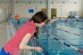 Trainer woman holding a stopwatch on poolside and conducts training