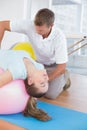 Trainer working with woman on exercise ball Royalty Free Stock Photo