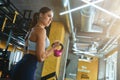 Training arms. Young strong athletic woman in sportswear exercising with dumbbells at industrial gym