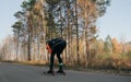 Training an athlete on the roller skaters. Biathlon ride on the roller skis with ski poles, in the helmet. Autumn