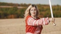 Training in the autumn field - a belligerent woman holding a sword