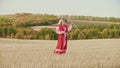 Training in the autumn field - a belligerent woman in red traditional dress wields with a sword