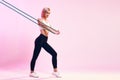 Training body . Side view of sporty young woman in white top and black leggings exercising with resistance band while Royalty Free Stock Photo