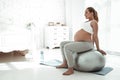 Peaceful long-haired woman doing exercises while sitting on pilates ball