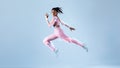 Futuristic training concept. Fit black woman in sportswear jumping, running