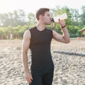 Training Outdoors. Athletic fit man drinking water after running workout at beach. Royalty Free Stock Photo