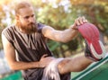 Training outdoors. Young man stretching his legs. Royalty Free Stock Photo