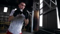 Training process of a young boxer in boxing studio, working out in puching gloves, practicing kicks