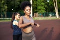 Training stretching the muscles in the fresh air. Two beautiful fitness females doing stretch exercises by stretching