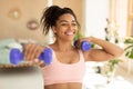 Training with weights. Happy african american woman doing exercises with dumbbells, strengthening her body at home Royalty Free Stock Photo