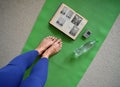 Training yoga female legs and book on a yoga mat top view green background