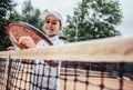 Training for young kid in tennis club. Portrait of little girl athlete looking in the camera near tennis net. Smiling sporty Royalty Free Stock Photo