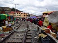 A trainrail in south america with ropes and other trass laying over and next to it and many people sitting alongside