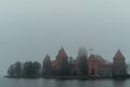 Trakai Island Castle - turreted castle on a tranquil island connected by footbridge with a Lithuanian culture museum during foggy
