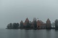 Trakai Island Castle - turreted castle on a tranquil island connected by footbridge with a Lithuanian culture museum during foggy