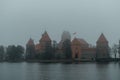 Trakai Island Castle - turreted castle on a tranquil island connected by footbridge with a Lithuanian culture museum during foggy