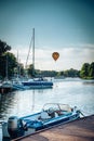 Boats parked by a dock at evening with hot air baloon flying by Royalty Free Stock Photo