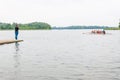 Photographer standing on pier and making pictures of a floating eight rowing boat with tourists and instructor in the waters of