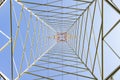 Electricity pylon in perspective seen from below with blue sky background