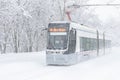 Tram goes along the street during snowstorm at winter in Moscow